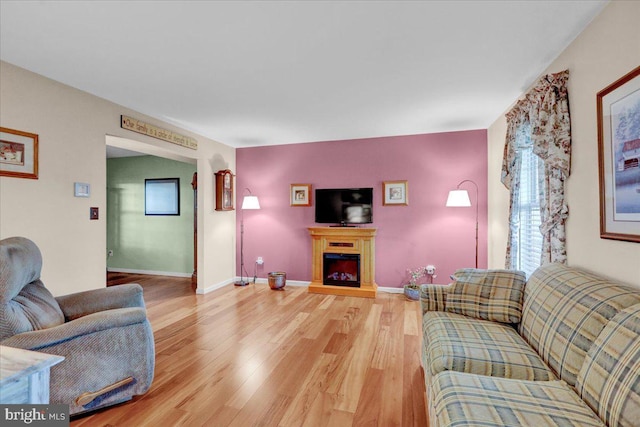 living room with a fireplace, baseboards, and wood finished floors