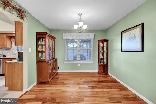 dining space featuring baseboards, light wood-style floors, and a notable chandelier