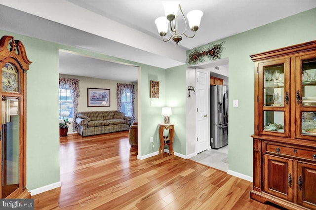 interior space with a chandelier, light wood finished floors, and baseboards