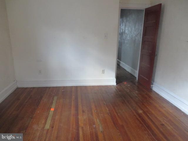 spare room featuring dark wood-style floors and baseboards