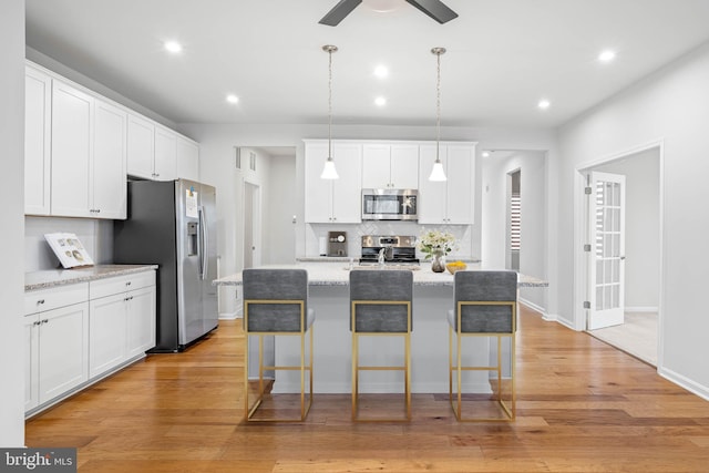 kitchen with a kitchen breakfast bar, appliances with stainless steel finishes, and light wood-style floors