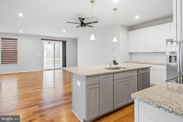 kitchen with stainless steel appliances, gray cabinets, a kitchen island with sink, a sink, and light wood-type flooring