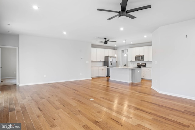 unfurnished living room with light wood-style flooring, baseboards, ceiling fan, and recessed lighting