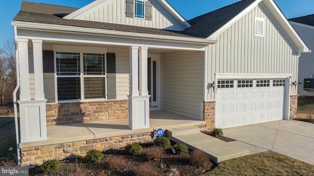 view of front of property featuring a porch, an attached garage, board and batten siding, stone siding, and driveway