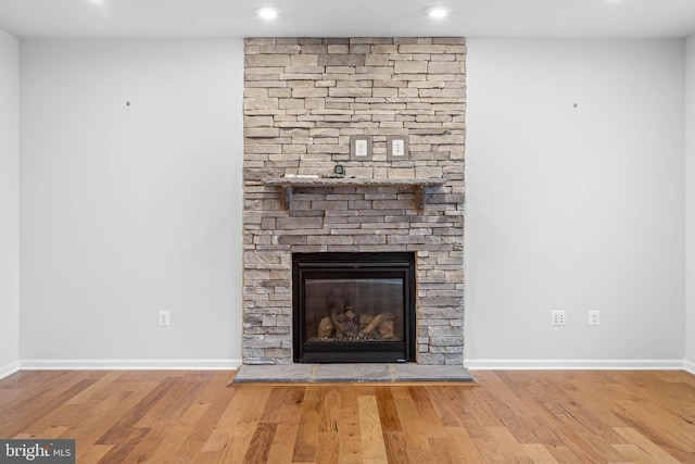 interior details with a stone fireplace, recessed lighting, wood finished floors, and baseboards