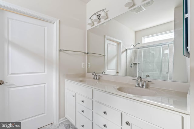 bathroom featuring double vanity, a stall shower, marble finish floor, and a sink