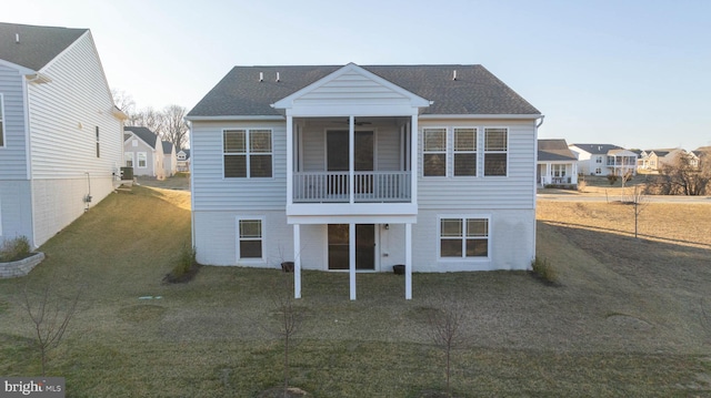 rear view of house with a sunroom, roof with shingles, and a yard