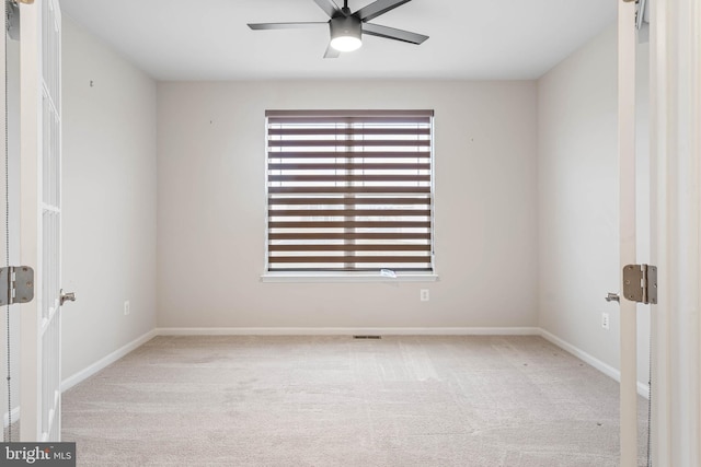 carpeted spare room featuring baseboards and a ceiling fan