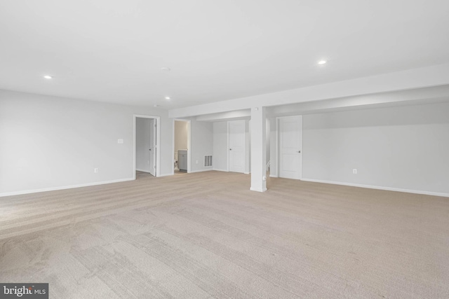 finished below grade area featuring light colored carpet, visible vents, and baseboards