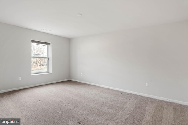 spare room featuring carpet flooring, visible vents, and baseboards