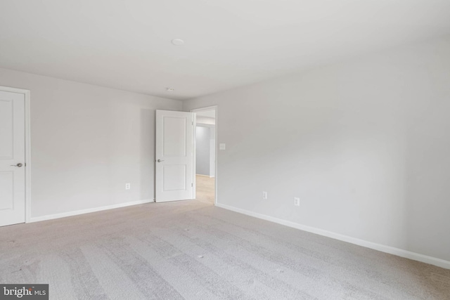 carpeted empty room featuring baseboards