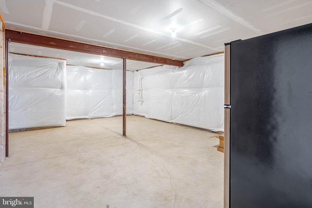 unfinished basement featuring freestanding refrigerator