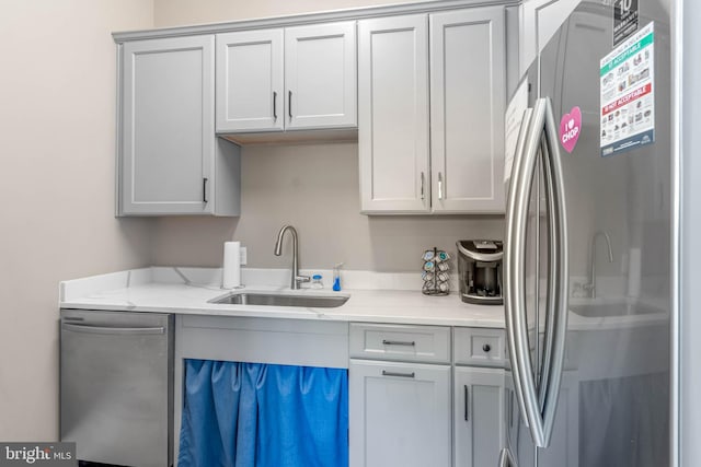 kitchen featuring appliances with stainless steel finishes, gray cabinets, and a sink