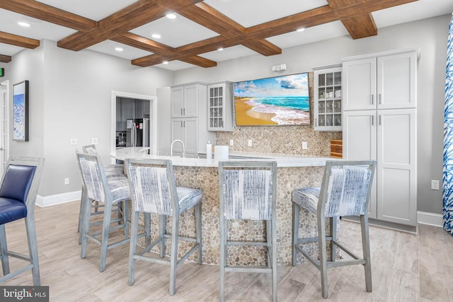 kitchen featuring baseboards, a breakfast bar area, coffered ceiling, and freestanding refrigerator