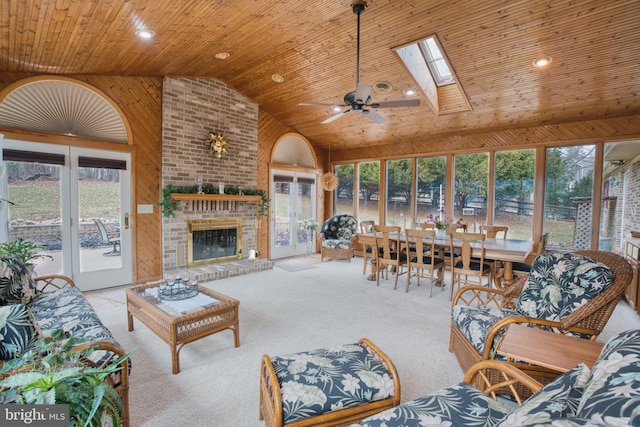 living room featuring wooden ceiling, a skylight, a fireplace, a ceiling fan, and carpet