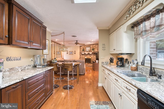 kitchen featuring dishwasher, a ceiling fan, light wood-style flooring, white cabinetry, and a sink