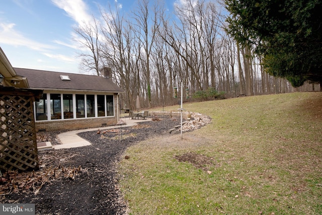 view of yard featuring a sunroom, a patio area, and a fire pit