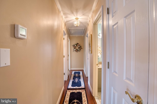 hallway featuring attic access, baseboards, and ornamental molding