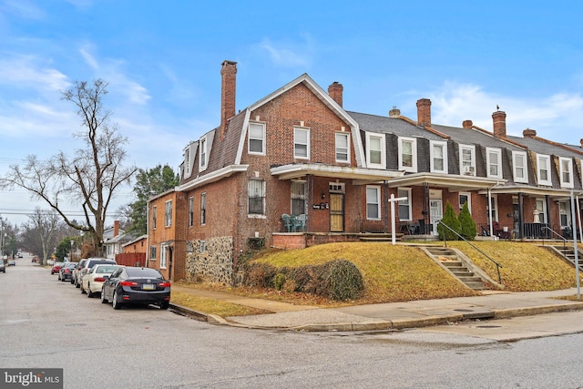 view of front of home with brick siding and a gambrel roof