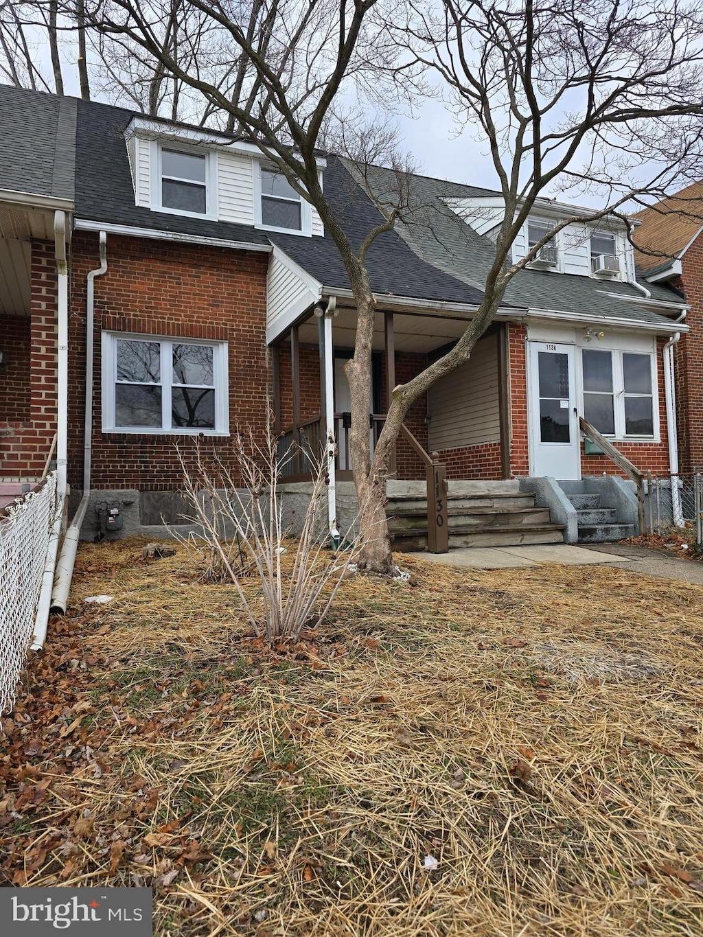 view of front of home with entry steps, brick siding, a shingled roof, and fence