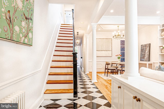 stairway featuring crown molding, radiator, decorative columns, and an inviting chandelier