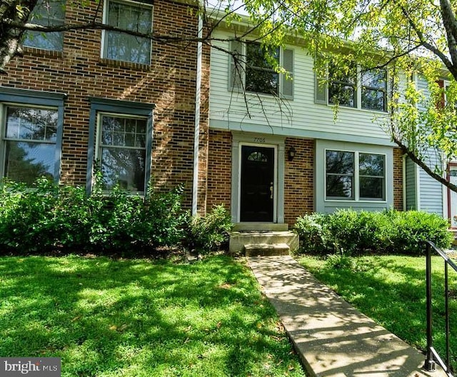 property entrance with a yard and brick siding