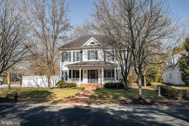 view of front of home featuring covered porch, a front lawn, and fence