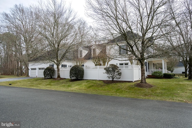 view of side of property with driveway, a yard, a fenced front yard, and an attached garage