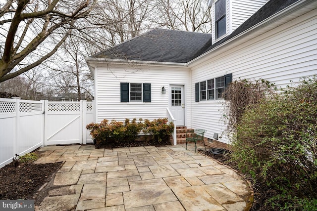 back of property featuring entry steps, a shingled roof, fence, a gate, and a patio area