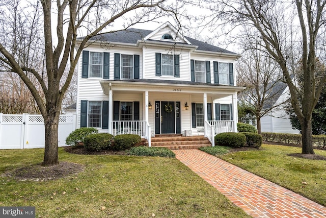 view of front facade with a porch, fence, and a front lawn