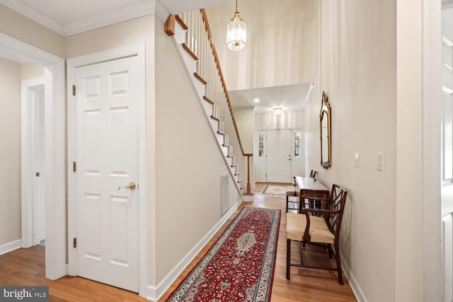 foyer with light wood finished floors, stairway, and baseboards