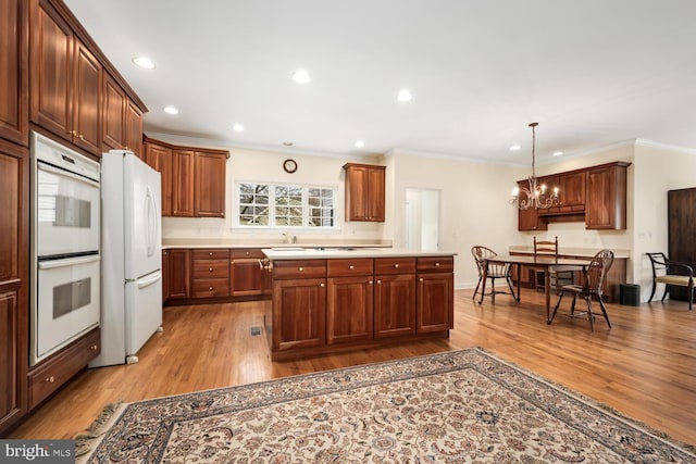 kitchen with white appliances, a notable chandelier, crown molding, and light wood-style flooring