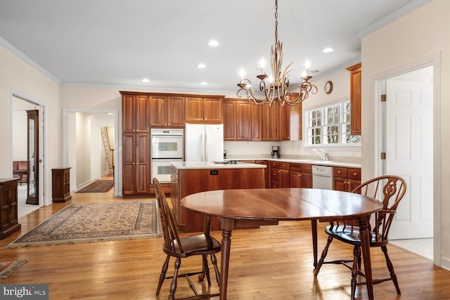 kitchen with light countertops, brown cabinetry, a kitchen island, wood finished floors, and white appliances