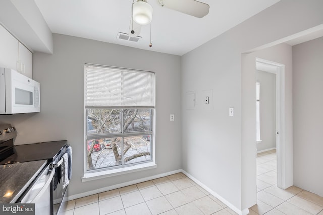 kitchen with visible vents, dark countertops, white microwave, stainless steel electric range, and white cabinetry