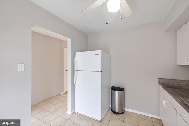 kitchen featuring light tile patterned floors, dark countertops, a ceiling fan, freestanding refrigerator, and white cabinets