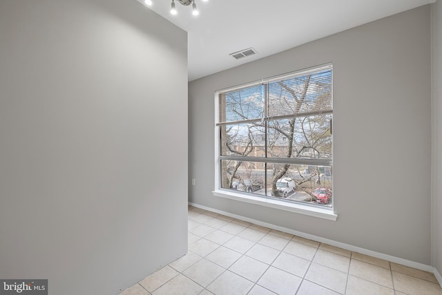 spare room featuring a healthy amount of sunlight, visible vents, baseboards, and light tile patterned floors