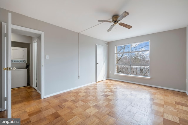 unfurnished bedroom featuring baseboards, a ceiling fan, and stacked washer / drying machine