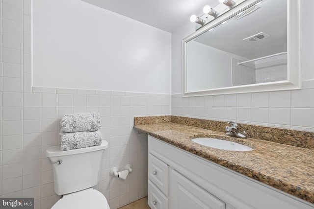 bathroom featuring visible vents, toilet, tile walls, and vanity