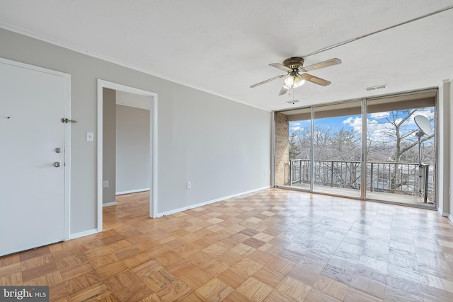 empty room with ceiling fan, a textured ceiling, visible vents, baseboards, and expansive windows