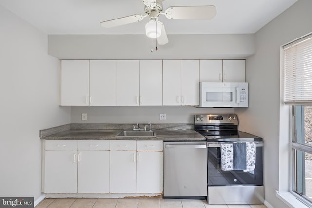 kitchen featuring stainless steel appliances, dark countertops, white cabinets, and a sink