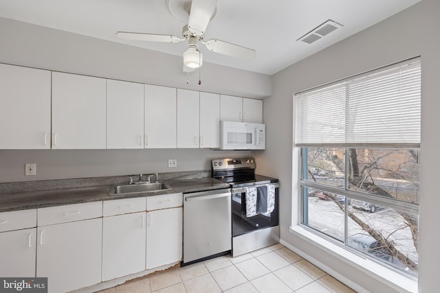 kitchen with stainless steel appliances, a sink, visible vents, white cabinets, and dark countertops