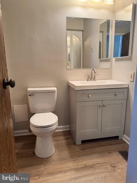 bathroom featuring toilet, baseboards, wood finished floors, and vanity