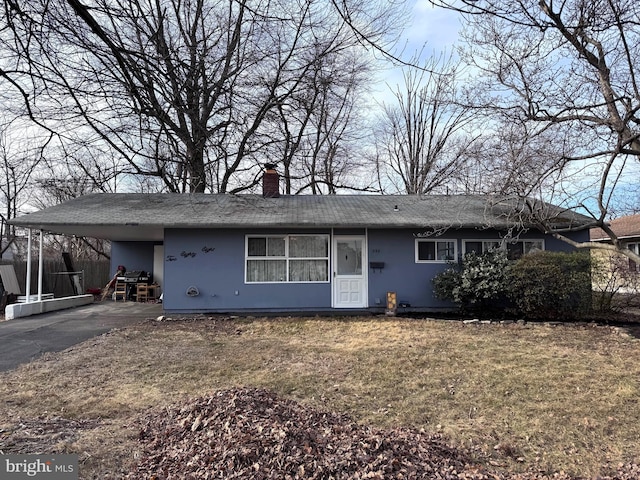 single story home featuring a carport, a chimney, a front yard, and driveway