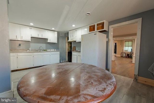 kitchen with recessed lighting, under cabinet range hood, white cabinets, light countertops, and freestanding refrigerator