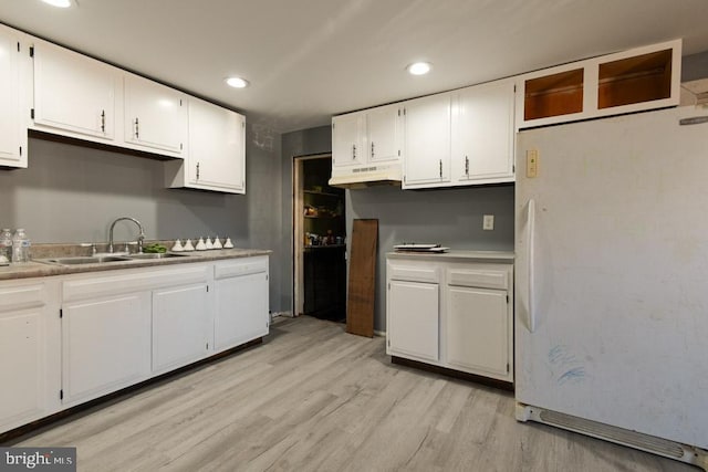 kitchen with freestanding refrigerator, light countertops, a sink, and white cabinetry