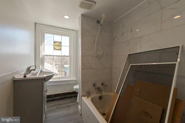 bathroom with recessed lighting, shower / bathing tub combination, toilet, vanity, and wood finished floors