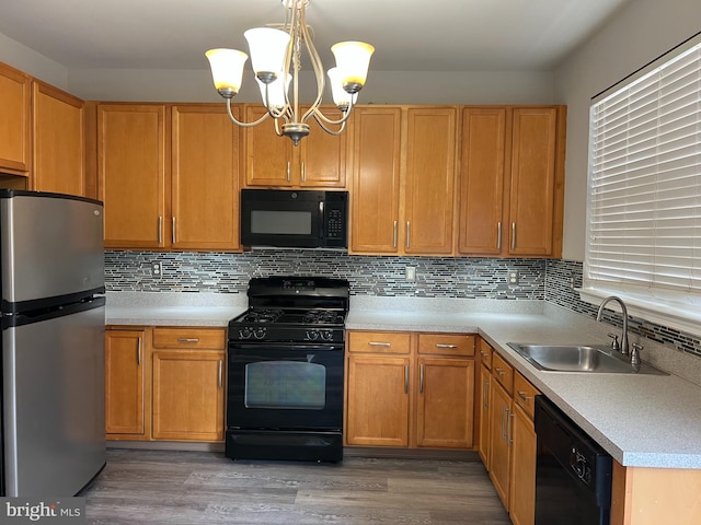 kitchen featuring black appliances, light countertops, a sink, and wood finished floors