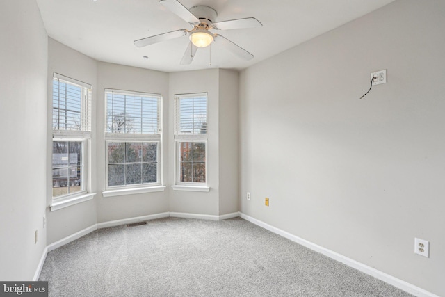 empty room with carpet, visible vents, ceiling fan, and baseboards