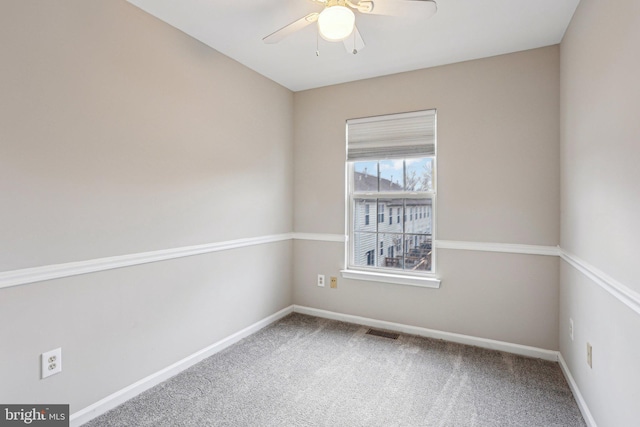 carpeted spare room with a ceiling fan, visible vents, and baseboards