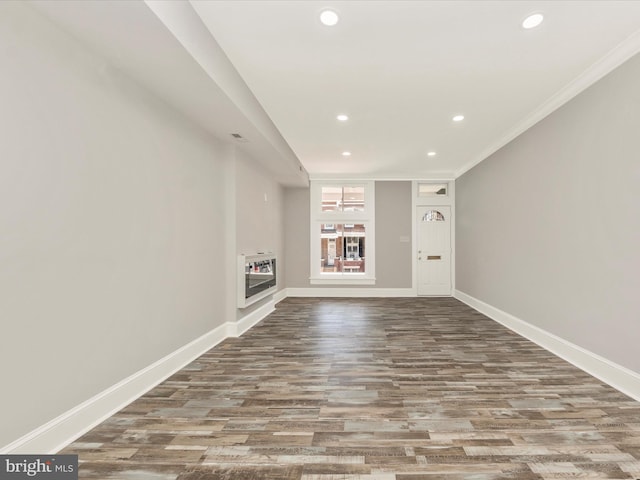 unfurnished living room with recessed lighting, crown molding, baseboards, and wood finished floors